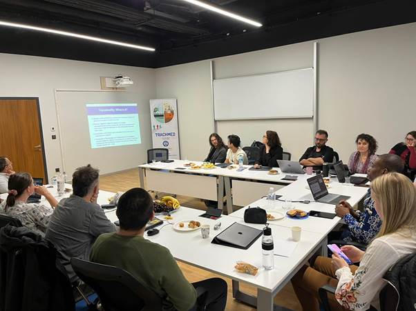 John Narh and other people sitting in a room during a presentation. 