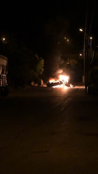 a vehicle in the middle of the road on fire in the night