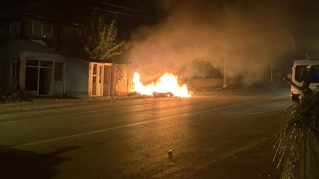 fire in the middle of the street by the building.
