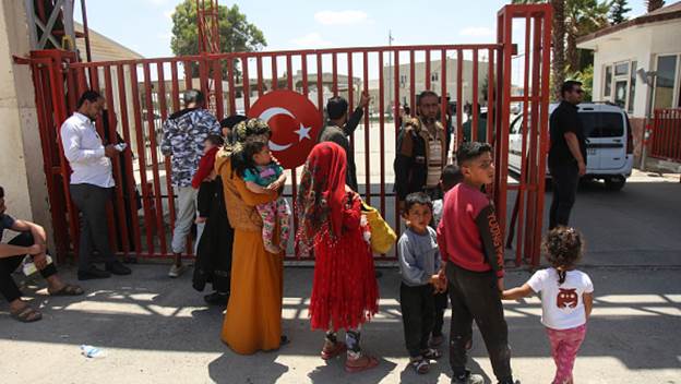 people standing by the gates with the turkish flag, children